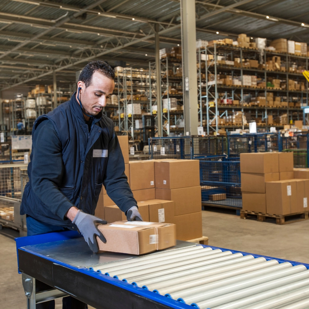 Fulfillment center staff sorting packages on automated conveyor belt.