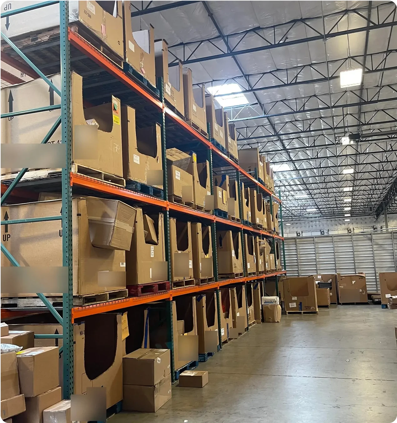 Tall industrial racking in a warehouse filled with organized rows of large, open-fronted cardboard pick bins used for inventory storage and order picking.